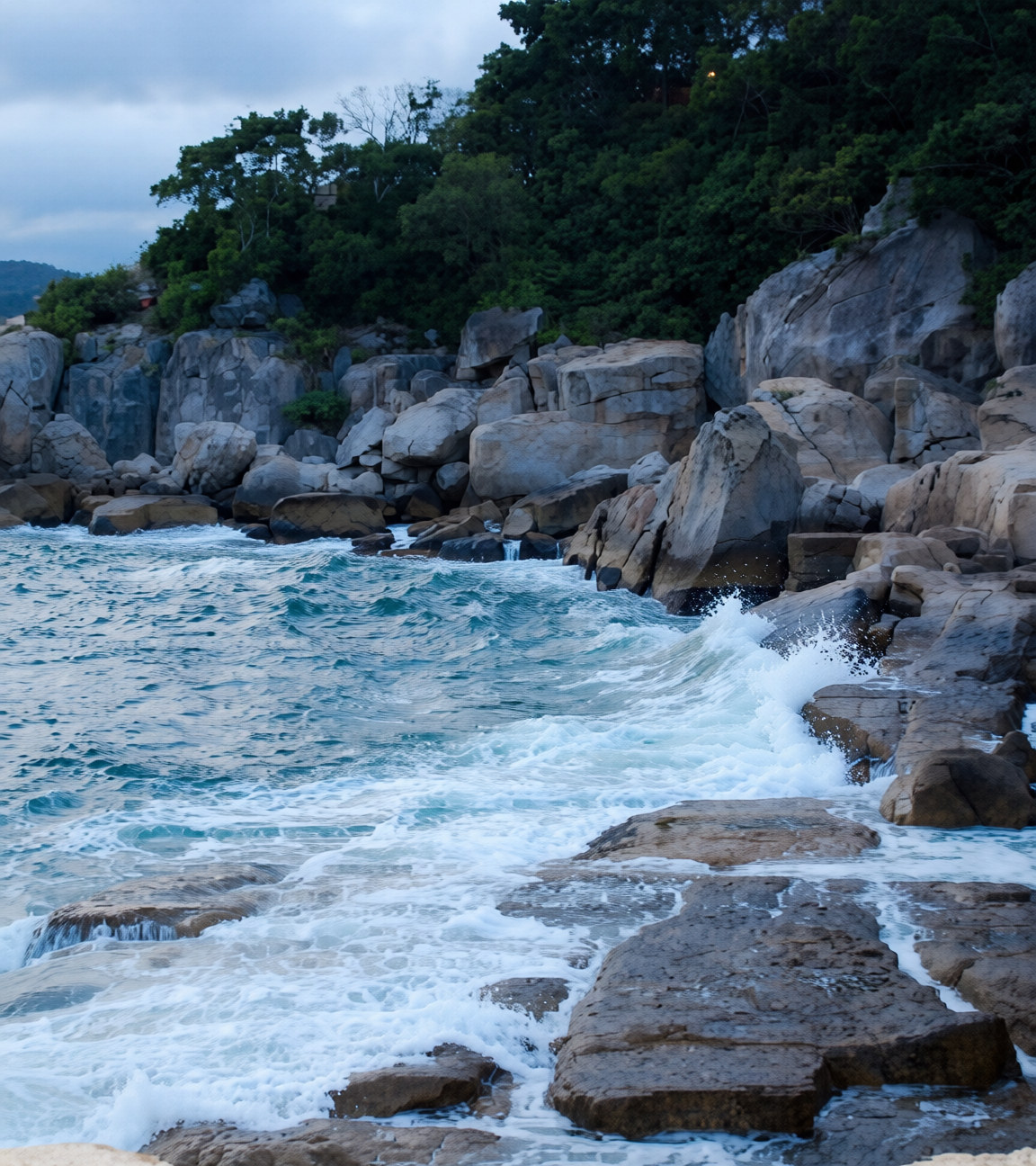 Rocky Hong Kong shoreline with waves crashing on boulders