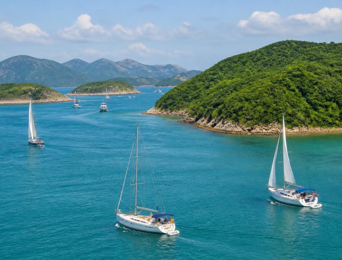 Sailboats cruising through clear water between Hong Kong's green islands