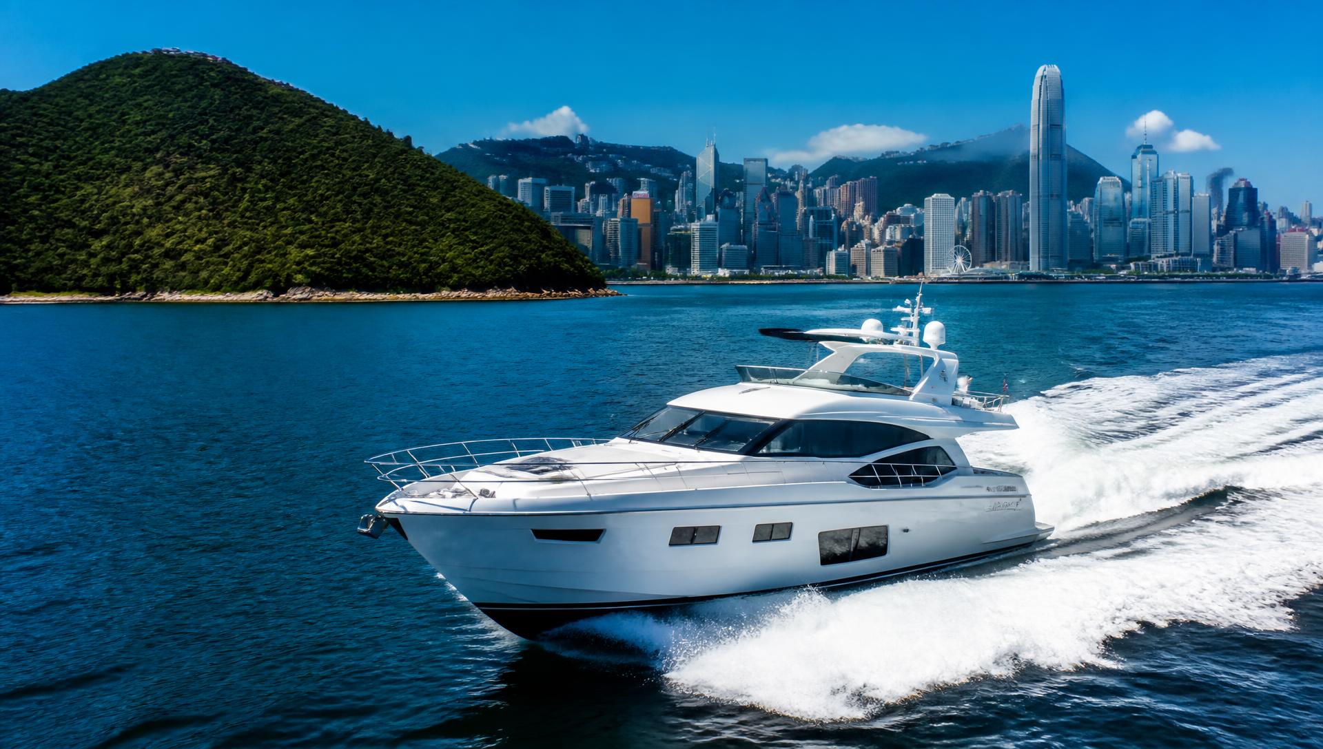 Luxury yachts sailing through Hong Kong waters with lush green islands and the premium harbour skyline